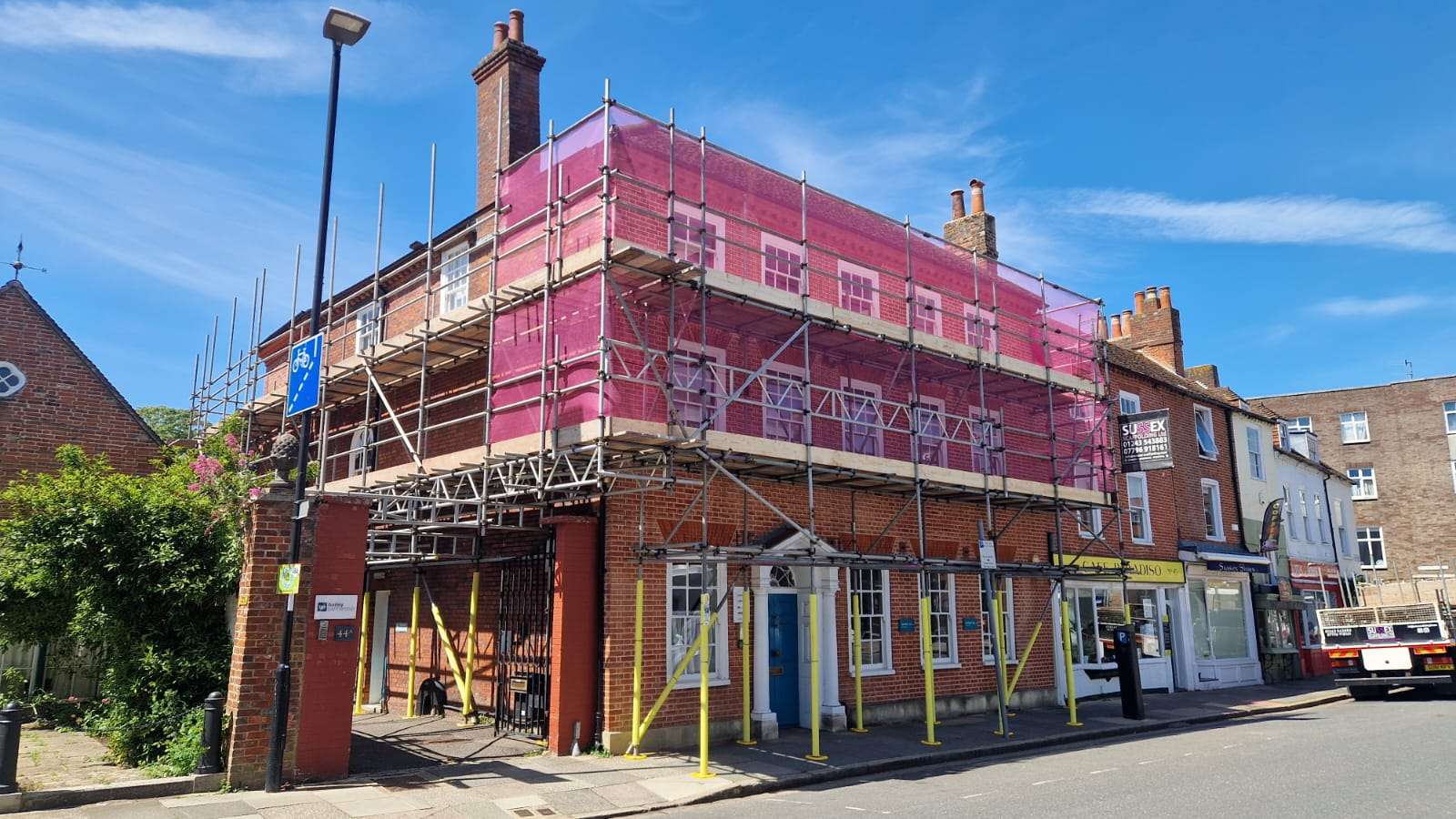 Commercial scaffolding with protective sheeting installed around a town centre building for safe access during refurbishment works